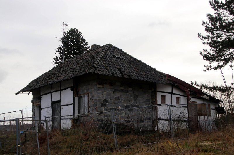 Overview of the Bouwberg cottage behind security fencing, 2019